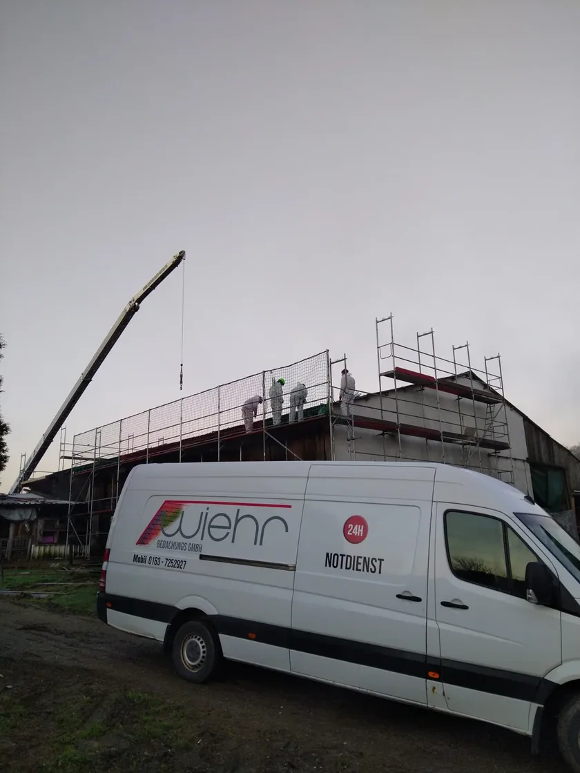 Dachbaustelle mit Gerüst, Fachkräften, Kran und Wiehr-Fahrzeug