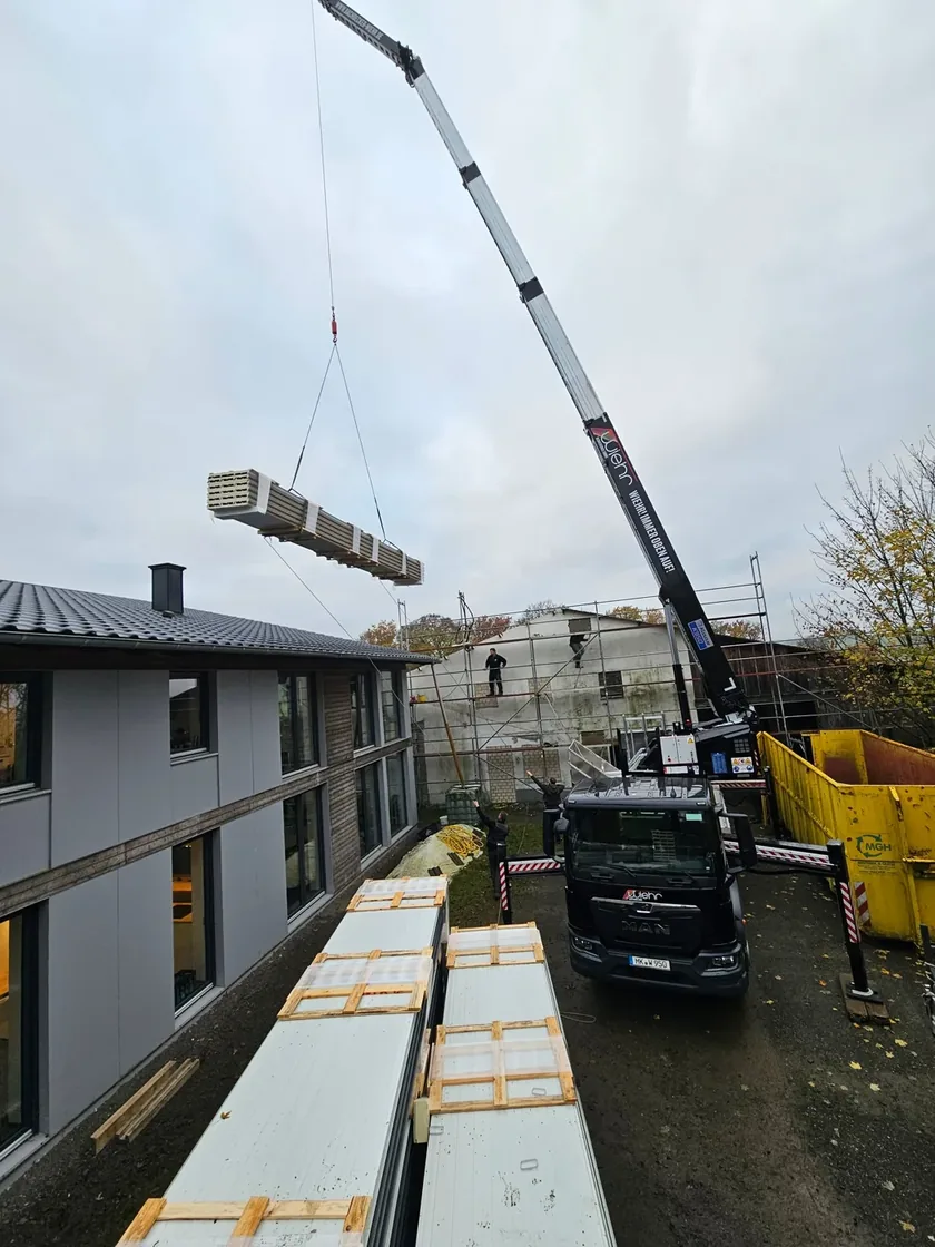 Kran hebt Paneel- und Materialpaket über die Baustelle