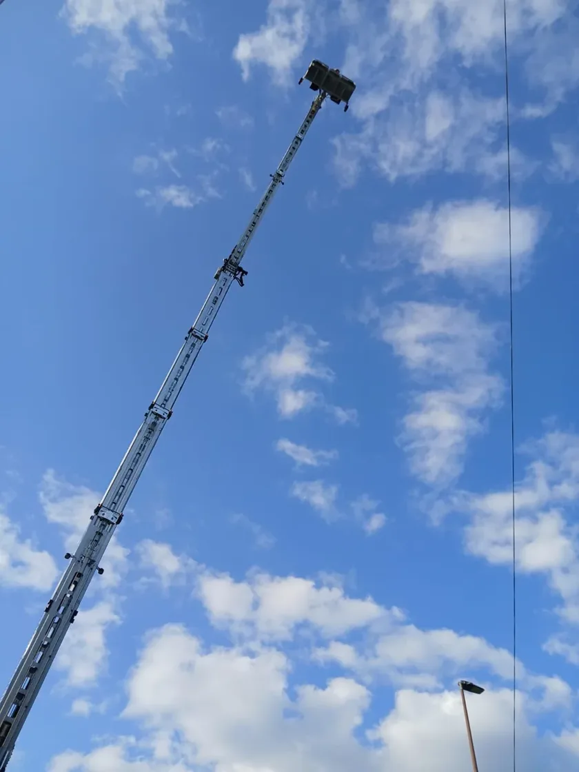Ausgefahrener Kranausleger mit Korb vor blauem Himmel