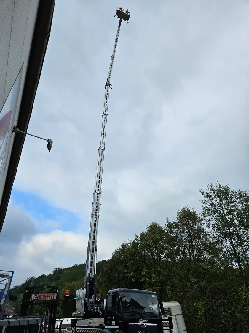 LKW-Kran mit voll ausgefahrenem Mast auf der Baustelle