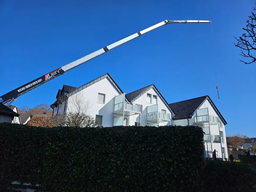 Wiehr-Kran über weißer Wohnanlage bei klarem Himmel