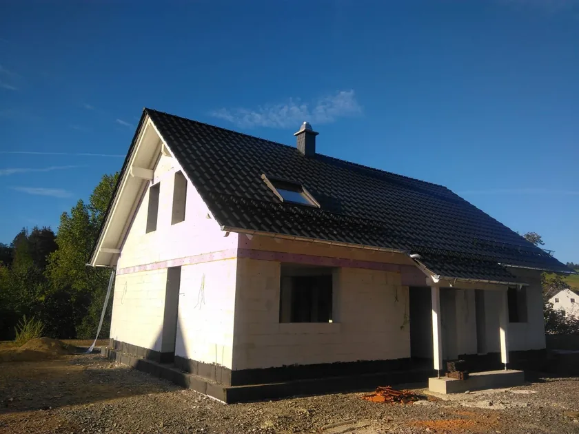 Neubau mit anthrazitfarbenem Steildach unter blauem Himmel