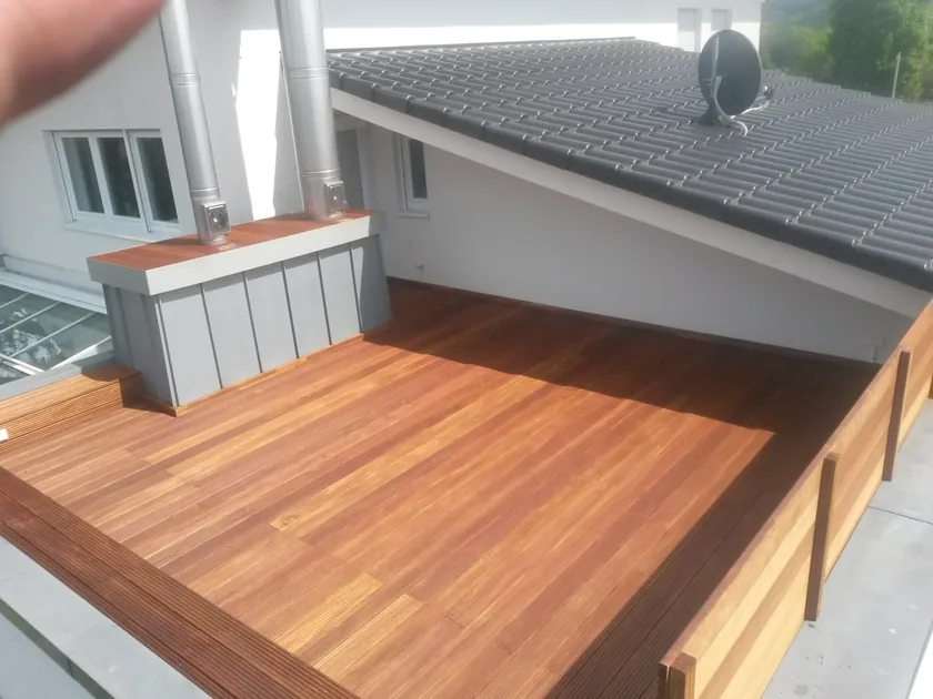 Dachterrasse mit Holzbelag und metallverkleidetem Schornsteinaufbau