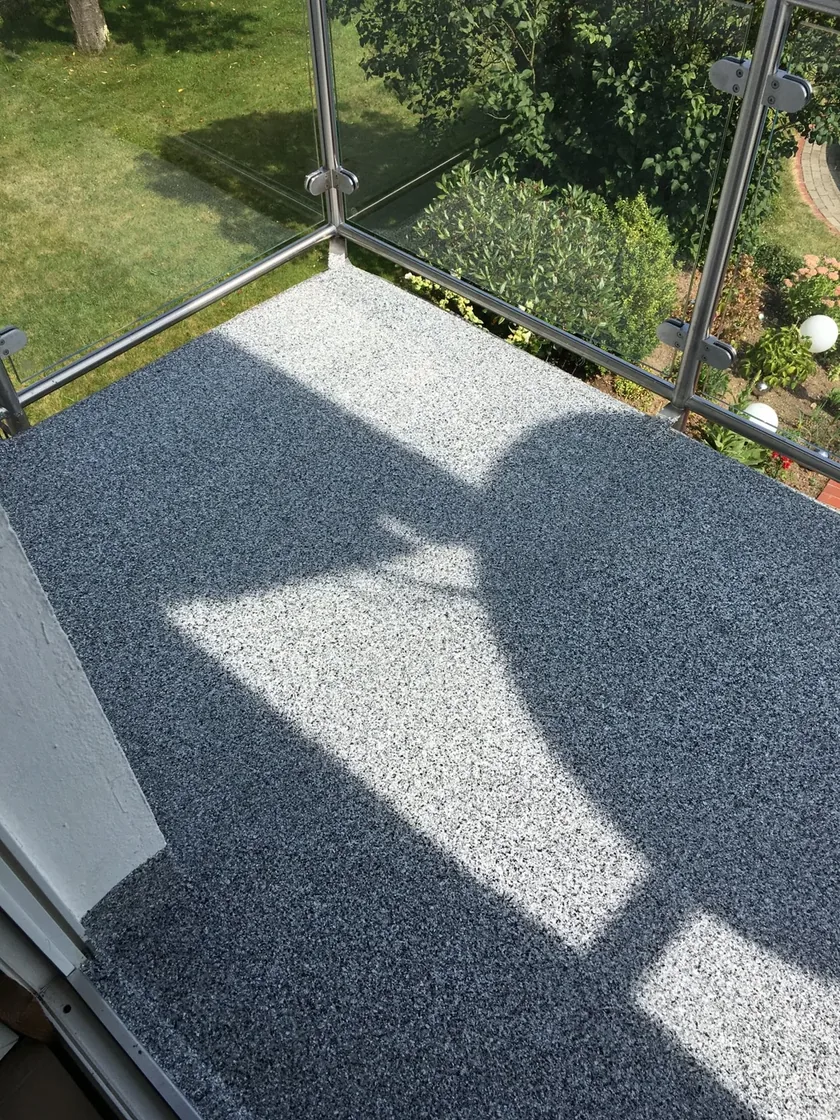 Balkon mit Steinteppichbelag und Glasgeländer